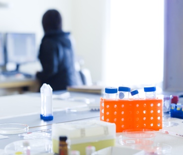 beakers on a table, with researcher in background