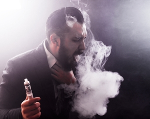 Man smoking e-cigarette, surrounded by a vape cloud, and coughing