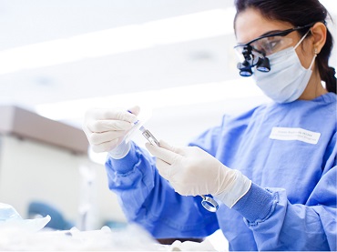 woman dressed in medical scrubs examines a specimen